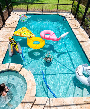 Sunny backyard pool bustling with colorful floaties and leisure.