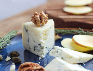 Blue cheese with nuts, capers and rosemary in a plate on a table
