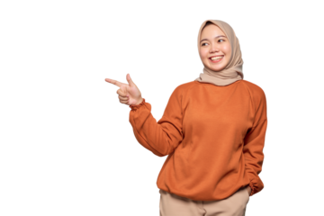Cheerful young Asian woman in orange shirt pointing fingers at copy space isolated on transparent background