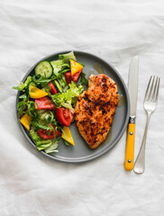 Balanced diet lunch - baked chicken breast and fresh vegetable salad on a light background, top view