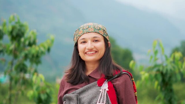 Portrait of traditional Himachali teenager girl looking at the camera with a smile while standing against mountain in Manali, Himachal Pradesh, India. Traditions and culture concept.
