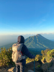 Fototapeta premium Man hiking Mount Merapi Morning View from Mount Merbabu – Scenic Volcanic Landscape in Indonesia