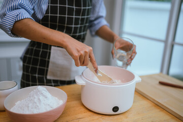 Adult woman kneads dough in a bright kitchen, hands dusted with flourpreparing homemade bread in a cozy, peaceful setting.