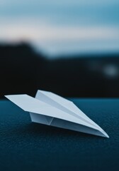  Photorealistic close-up of a simple white paper airplane resting. Travel industry visuals, creative agency branding, communication concepts, education themes (simple engineering), childhood nostalgia