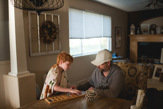 Father and son bonding over board game in cozy sunlit home setting