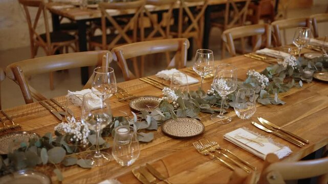 Elegant rustic wedding dinner table setting with glassware gold cutlery and floral decor