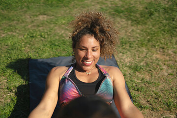 Smiling fitness trainer doing sit-ups outdoors on grass during sunny day