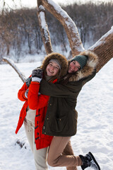 Two girls in winter, in warm clothes, enjoying the snow, outdoor. Cold time of the year, laughter and fun. Winter forest, white glade.