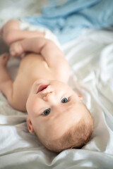  Portrait of a baby boy lying on a white bed. The child is 4 months old. Happy morning of the baby.
