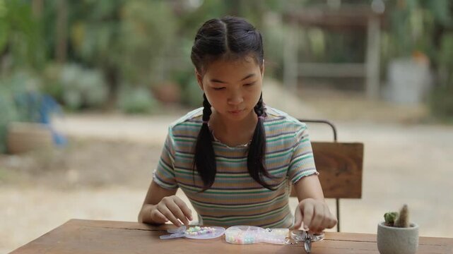 Asian girl making handmade necklace accessories