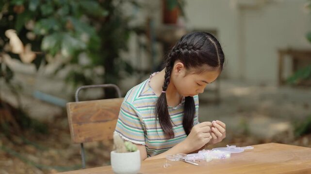 Asian girl making handmade necklace accessories