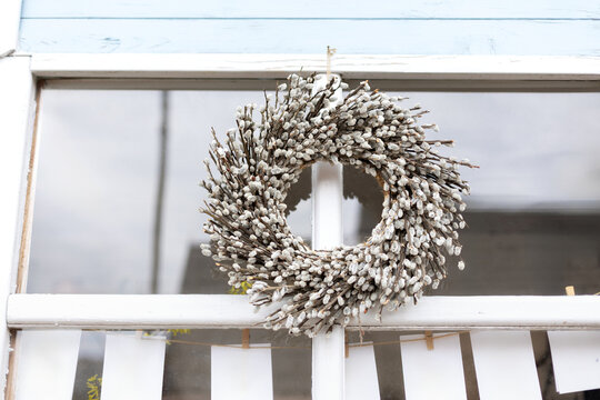Woven brown hanging willow wreath from wickers on window. Traditional seasonal spring holiday decoration. Rustic circle willow wreath. Copy space
