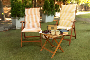Wooden deckchair and vintage radio near campsite. Sunbed in garden. Cozy interior courtyard with table, chairs with Retro FM radio player and sun loungers in backyard. Garden furniture for leisure 