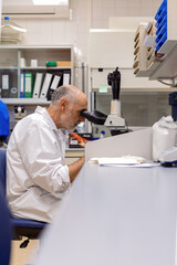 Researcher in a laboratory observing samples with a high-precision microscope
