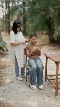 Asian mother braids her daughter's hair