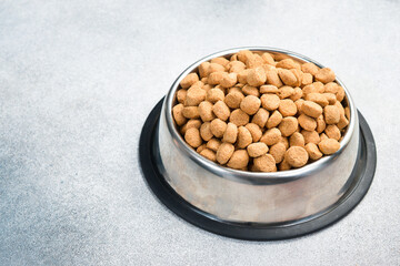 Dog food in a silver bowl. Dry animal feed in a bowl close up.
