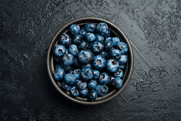 Close-up of blueberries in a bowl on a black slate table.