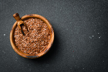 Wooden bowl with flax seeds, on a dark background. Organic food, superfood. Top view.