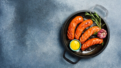 Fried homemade sausages in a metal pan. On a gray concrete background.