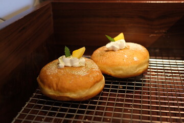 A selection of gourmet donuts topped with a variety of colorful icings, creams, and toppings such as caramel, fruit slices, and sprinkles, arranged neatly on a cooling rack. High quality photo