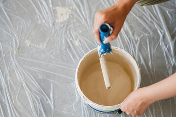 a beige can of paint with paint roller on floor