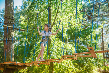 Child confidently explores a rope bridge in an adventure park, showcasing bravery and balance