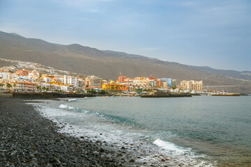Coastal view of Candelaria town in Tenerife with colorful buildings featuring volcanic pebble beach