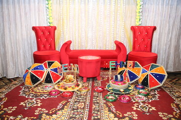 red sofa and armchair, Pakistani Indian bridesmaids holding henna plate, colorful handmade pottery,...