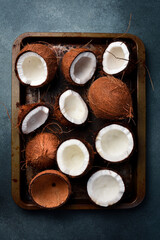 Fresh open coconuts on a metal tray. Tropical nuts close-up. On a dark background.