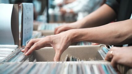 A man browsing vinyl records in a music store, surrounded by retro albums in physical format - Powered by Adobe
