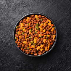 Bowl of pet food. Nutritious healthy diet pet food. On a black textured background.