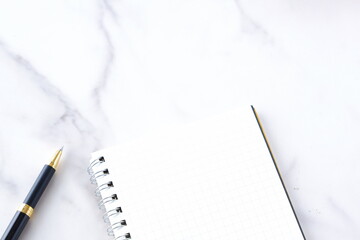 リング式のメモ帳とペンでデスクワークをしているイメージ
