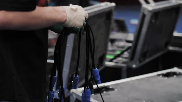 Worker holding power cables near open transport cases