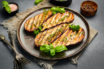 A plate of grilled eggplant. Grilled vegetables. Top view. On a gray concrete background.