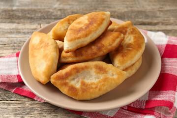Delicious fried pyrizhky (stuffed pies) on wooden table, closeup