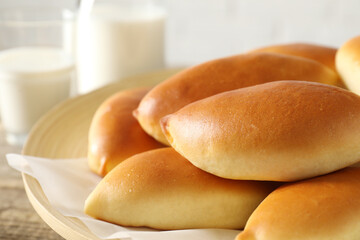 Tasty baked patties and milk on wooden table, closeup