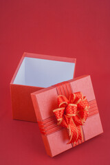 Open red gift box with ribbon on red background