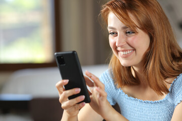 Happy woman browsing phone at home
