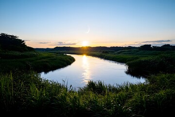 Serene sunset over a tranquil river, reflecting golden light on calm waters, lush green banks