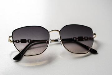 Close-up of stylish sunglasses with dark lenses and metal frame on a white background