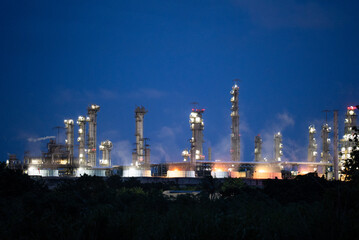 Obraz premium Background of a petrochemical and refinery oil industrial at night view, distillation column, drum and pipeline. Gas, diesel and chemical business