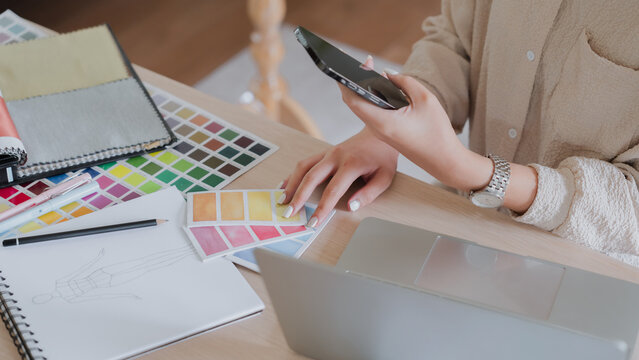 Creative designer woman taking notes and working about graphic design on laptop in home studio