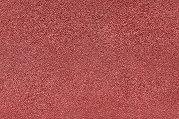 Grainy texture of asphalt, plaster, cement, plastic, rock, stone close up, macro. Background of red colored granular wall surface, rough backdrop