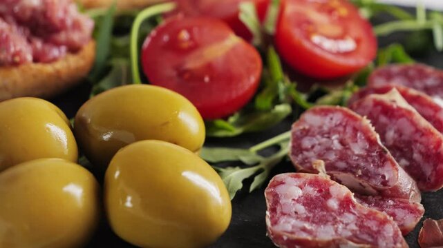 Set of delicious Spanish snacks in the restaurant, jamon, sausage fuet large green olives. High quality 4k footage