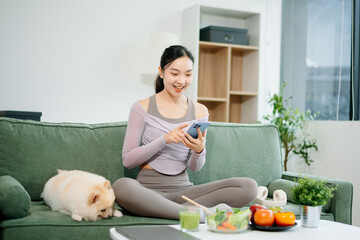 Fit woman enjoys fresh salad, fruits, and juice in a modern kitchen, showcasing wellness,...