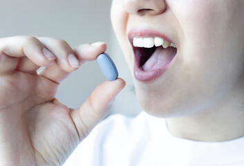 Close up of woman smiling and holding pill. Taking medicine. Healthcare concept