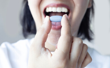Close up of woman smiling and holding pill. Taking medicine. Healthcare concept