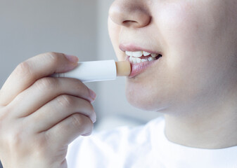 Woman applying lips balm to her lips. Closeup of lip protection	