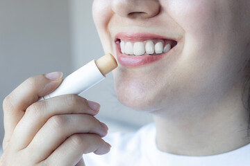 Woman applying lips balm to her lips. Closeup of lip protection