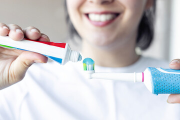 Close up of Smiling woman applying toothpaste on toothbrush in bathroom.